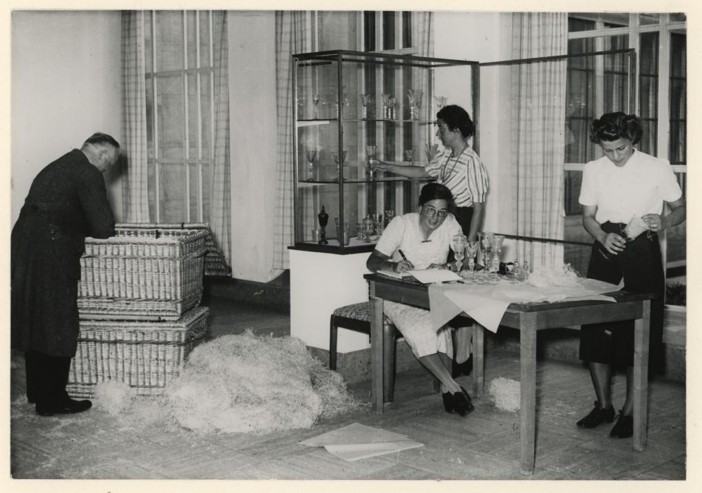 Afb. 13. Het inpakken van glaswerk in Museum Boymans. Zichtbaar zijn de medewerkers: (van links naar rechts) Van der Heijden, Hermine Crol, Tinta Drost (staand) en Bernardine de Neeve, 1939, XXXIII-537-1, Stadsarchief Rotterdam. Foto: Erich Adolf Hof